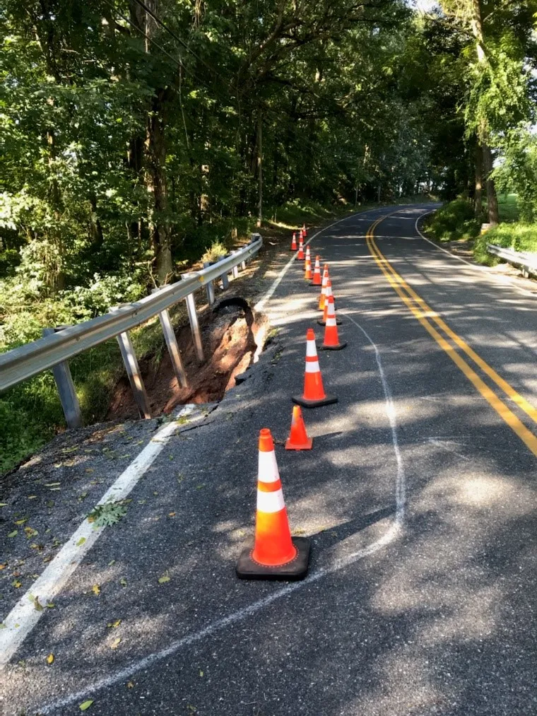 An image of orange safety cones with a white chalk outline on a blacktop road to mark where to start digging into the roadway section that is to be repaired.